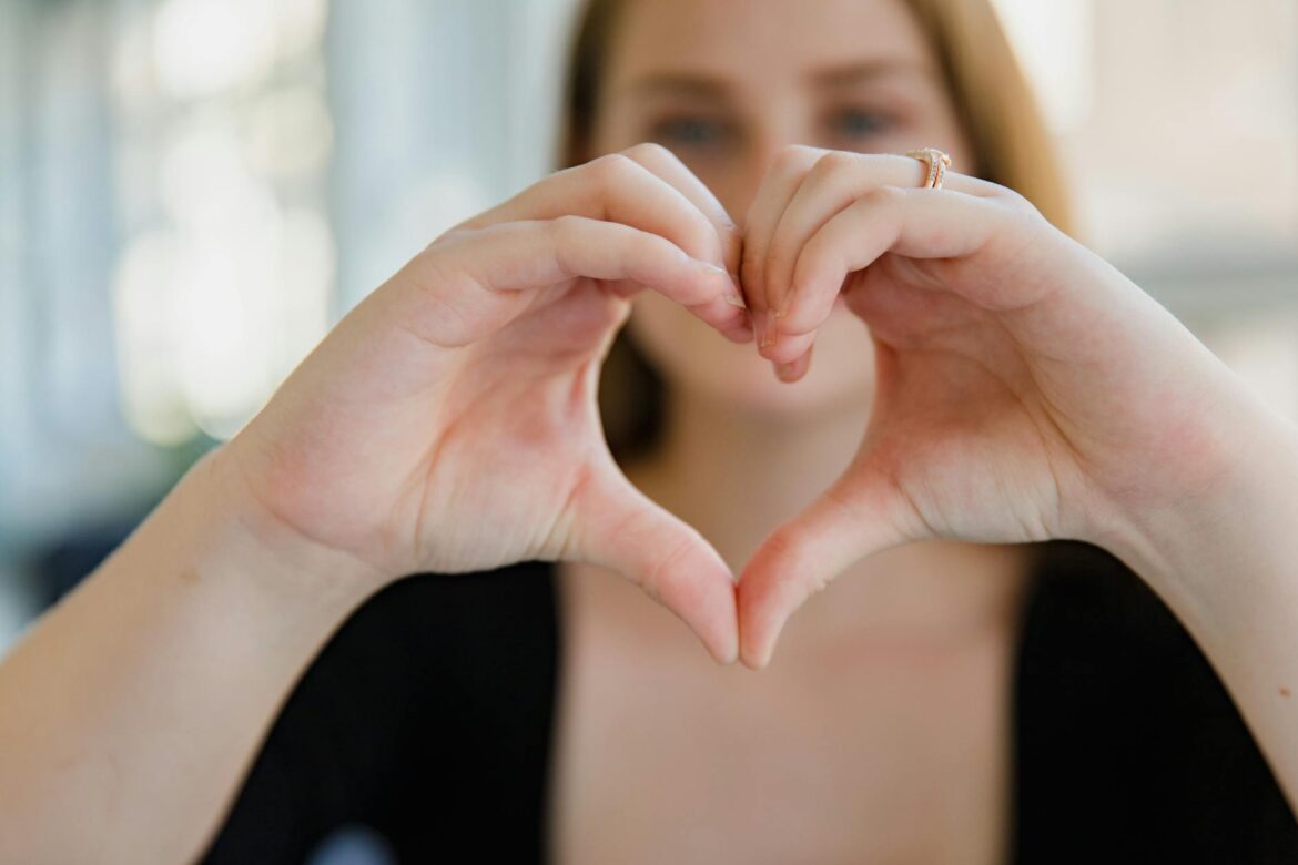 close up of woman showing heart hand sign